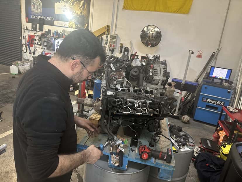 Mecanic CDC Service Auto lucrând la un motor în atelier